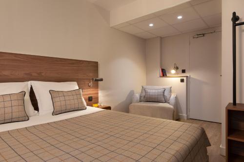 a hotel room with a bed and a chair at Maison Barbillon Grenoble - Centre Gare in Grenoble