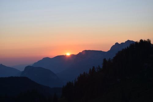 a sunset over a mountain range with the sun setting at Herbst Wohnerlebnis in Lofer