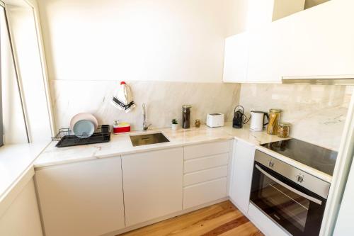 uma cozinha branca com armários brancos e um lavatório em Guest H4U - Porto Batalha City Center no Porto