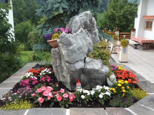 a garden with flowers and a rock and a bird at Haus Enzian in Thiersee