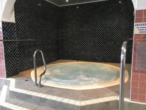 a jacuzzi tub in a bathroom with black tiles at Macdonald Plas Talgarth Resort in Aberdyfi