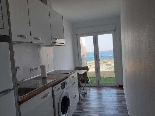 a white kitchen with a view of the ocean at Apartamento muelle in Pozo Izquierdo