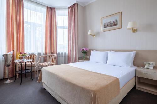 ein Hotelzimmer mit einem Bett und einem Tisch in der Unterkunft Bristol Hotel in Sankt Petersburg