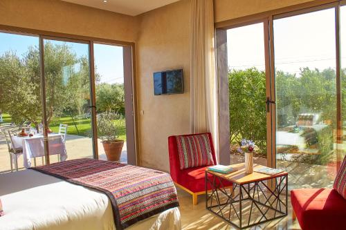 a bedroom with a bed and a chair and a balcony at Villa Jardins D'Isa in Marrakech