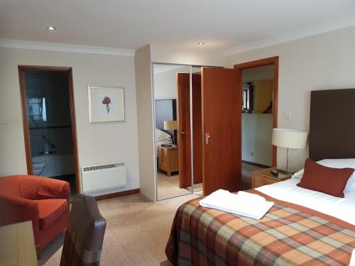 a hotel room with a bed and a chair at Macdonald Plas Talgarth Resort in Aberdyfi