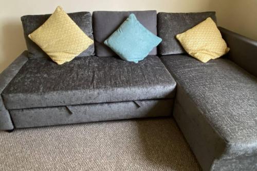 a gray couch with two blue and yellow pillows on it at River Walks Retreat in Bothal