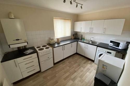 uma cozinha com armários brancos e um forno com placa de fogão em River Walks Retreat em Bothal