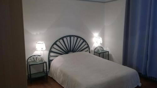 a bedroom with a white bed and two night stands at Villa à 100 m de Tarbes sud in Laloubère