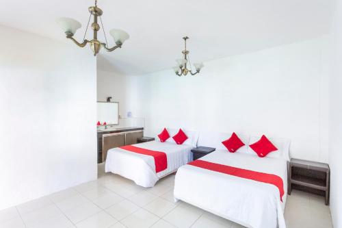 two beds in a white room with red pillows at OYO Hotel Rio in Subteniente López