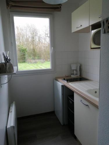 a small kitchen with a window and a sink at Entre le Pont 9 et l'Eveque , Les Hauts de Honfleur, Piscine, WIFI et Parking gratuits in Équemauville