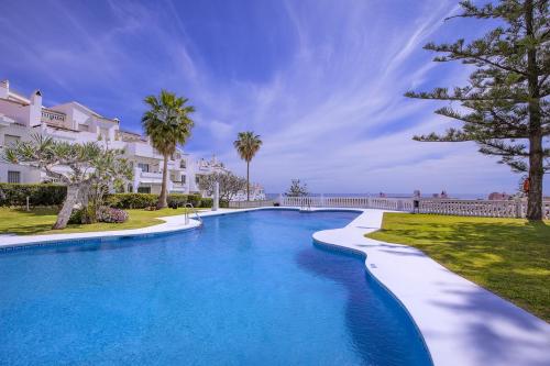 a swimming pool in front of a villa at Apartamentos Torrenueva Park in La Cala de Mijas