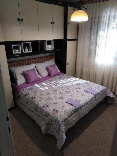 a bedroom with a large bed with purple pillows at Apartman Mimi in Klenovica