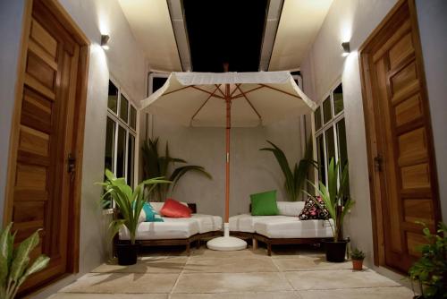een veranda met twee witte banken en een paraplu bij Escapism Maldives in Feridhoo
