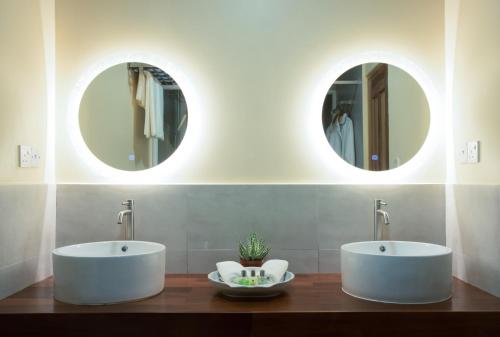 two sinks in a bathroom with two mirrors at Escapism Maldives in Feridhoo