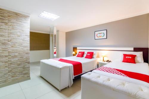 een slaapkamer met 2 bedden en rode kussens bij OYO Hotel Via Universitária, Anápolis in Anápolis