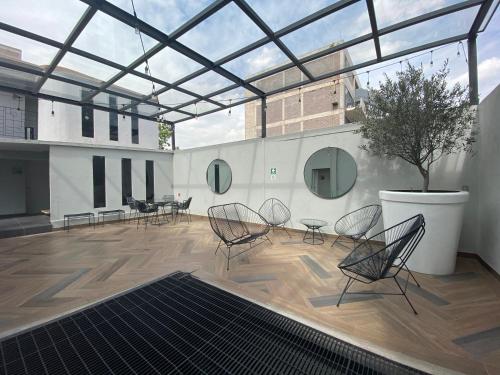 a patio with chairs and a tree on a building at Suites Alcazar in Mexico City