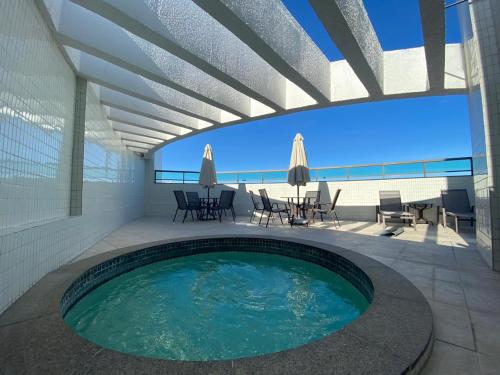 a swimming pool on a patio with a table and chairs at Apartamento de Luxo em Boa Viagem Perto da Praia. in Recife
