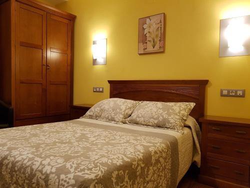 a bedroom with a bed and a dresser and lights at Hotel Reina Isabel in Medina del Campo