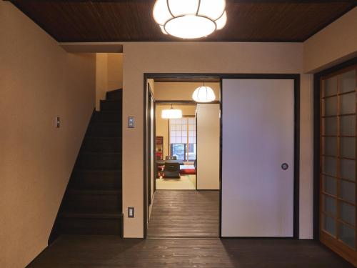 un pasillo con una puerta blanca y una escalera en Rinn Kujofujinoki West, en Kioto