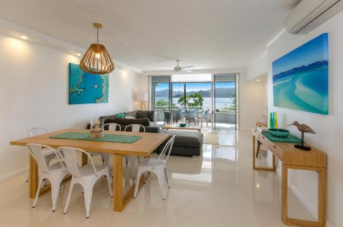 a dining room and living room with a table and chairs at Frangipani Apartments on Hamilton Island by HIHA in Hamilton Island