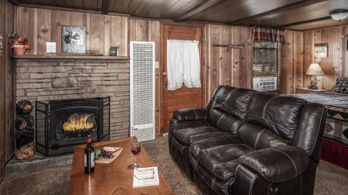 a living room with a leather couch and a fireplace at Canyon Cabins in Ruidoso