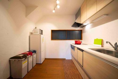 a kitchen with a white refrigerator and a sink at 仙石原Yorokobu 金時ヒルハウス 金時山登山に便利 BBQ in Sengokuhara