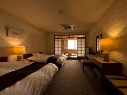 
a hotel room with two beds and two lamps at Ryochiku Bettei in Beppu

