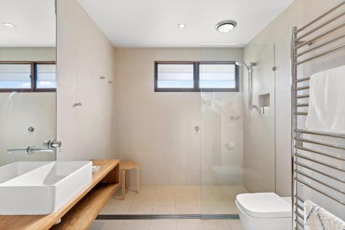 a white bathroom with a sink and a shower at Florida on Carlyle Street in Byron Bay