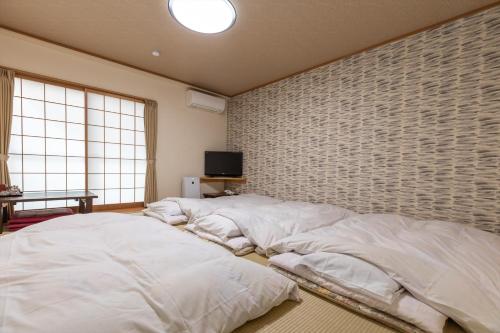 two large beds in a room with a brick wall at Business Ryokan Akashiya Annex in Akashi
