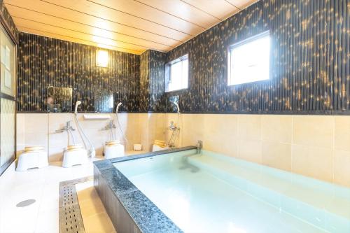 a bathroom with a tub and a tile wall at Business Ryokan Akashiya Annex in Akashi