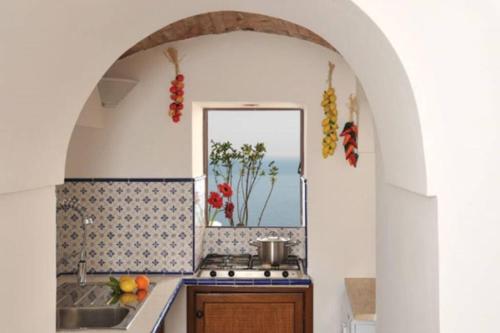 Una cocina con fregadero, estufa y ventana. en Villa Profumo di Mare con vista mozzafiato, en Positano