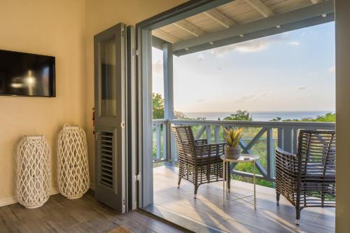 a room with a balcony with chairs and a table at West Rock Villas in Saint James