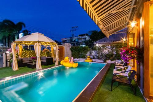 Ein Pool mit aufblasbaren Gummienten in einem Garten bei Nacht in der Unterkunft Bronte BnB in Cha-am