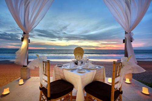 a dinner table on the beach at sunset at The Seminyak Beach Resort & Spa in Seminyak