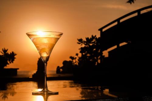 a candle in a wine glass with the sunset in the background at The Seminyak Beach Resort & Spa in Seminyak