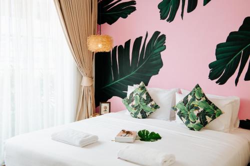 a bedroom with a white bed with a pink wall at Summer Stay Sattahip in Sattahip