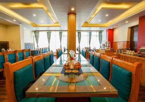 une salle à manger avec une grande table et des chaises bleues dans l'établissement Hotel Nalanda Ladakh, à Leh