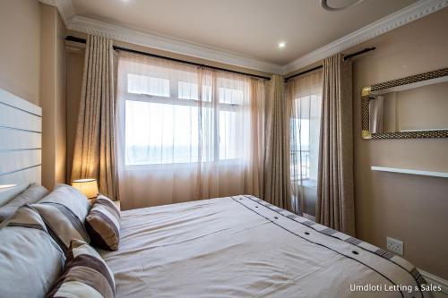 a bedroom with a large bed and a window at Cozumel 411 in Umdloti