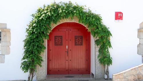 Une porte rouge avec un fond vert autour de celle-ci dans l'établissement Relais Des Tilleuls, à Hasparren