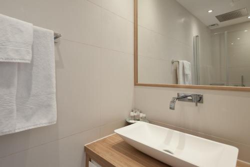 La salle de bains blanche est pourvue d'un lavabo et d'un miroir. dans l'établissement Superbe T3 sur la Marina de Bonifacio, à Bonifacio