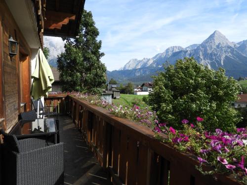a balcony with flowers and mountains in the background at Haus Goldeck in Lermoos