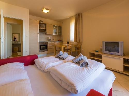 a room with a bed with white sheets and a tv at Apartments Villa Vanda in Selce