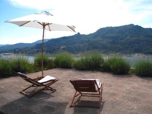 two chairs and an umbrella on a patio at Casa do Castanheiro in Outeiro