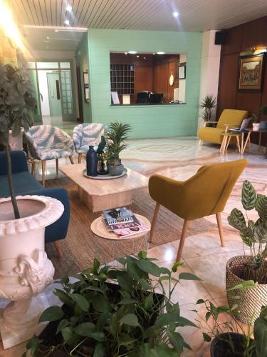 a lobby with chairs and potted plants at Hotel Marqués de Santillana in Torrelavega