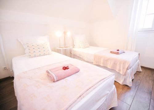 2 camas con sábanas blancas y una toalla rosa. en Maison la pointe, en Le Tampon