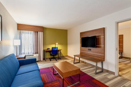 a living room with a blue couch and a desk at Holiday Inn Express Tampa-Brandon by IHG in Brandon