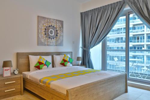 a bedroom with a bed and a large window at OYO 512 Home Skycourt Tower 1217, 1BHK in Dubai