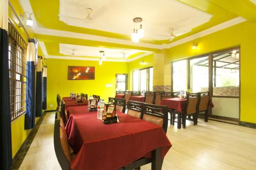 a restaurant with red tables and chairs and yellow walls at Lumbini Guest House in Lumbini
