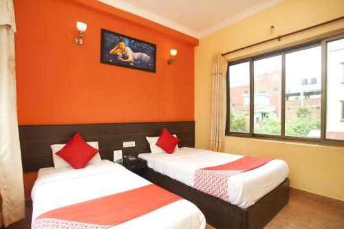 two beds in a room with orange walls at Lumbini Guest House in Lumbini