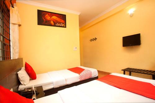 a bedroom with two beds and a tv on the wall at Lumbini Guest House in Lumbini